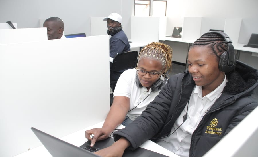 Wheelset Academy students working together on a computer during training, guided learning with headphones in a modern digital lab