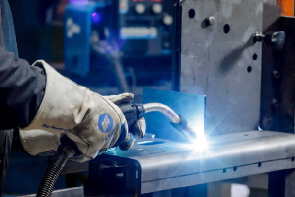 Welder performing metal joining with a MIG torch during CO2 welding course training at Wheelset Academy.