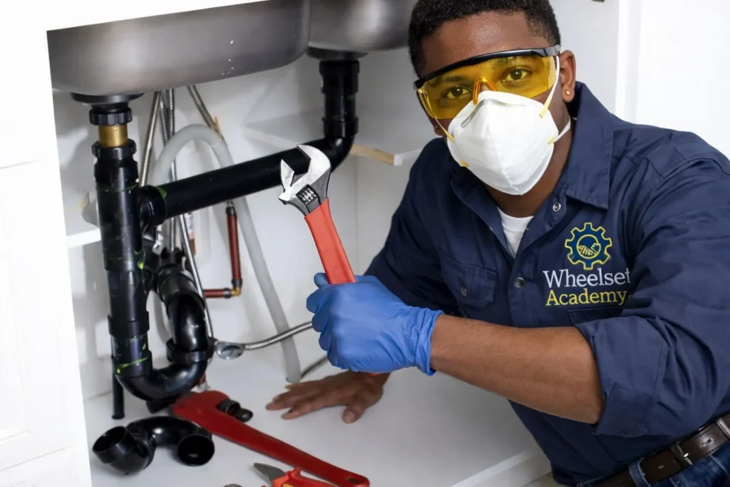 Learner performing sink pipe repair during a plumbing course practical at Wheelset Academy