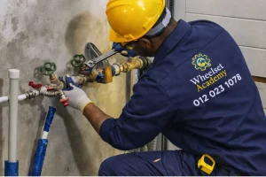 Learner installing and adjusting water pipe valves during practical plumbing course training