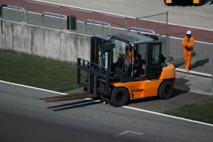 Pallet Lift Truck F12 Driver operating a powered pallet truck in a warehouse during material handling and pallet transportation operations.
