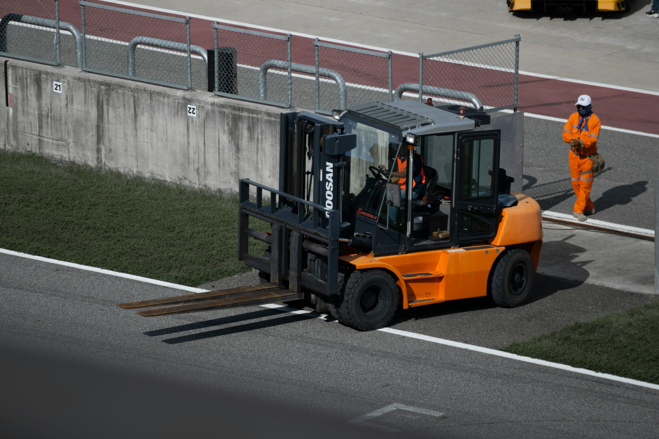 Pallet Lift Truck F12 Driver operating a powered pallet truck in a warehouse during material handling and pallet transportation operations.