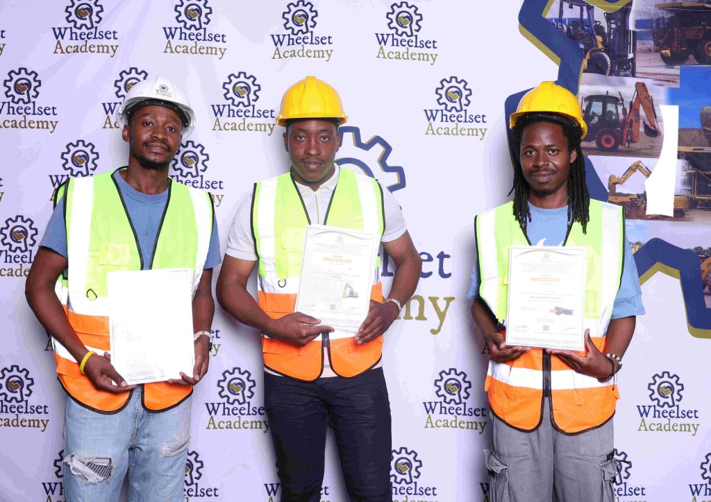 Three Wheelset Academy learners in safety gear holding the certificates they were awarded
